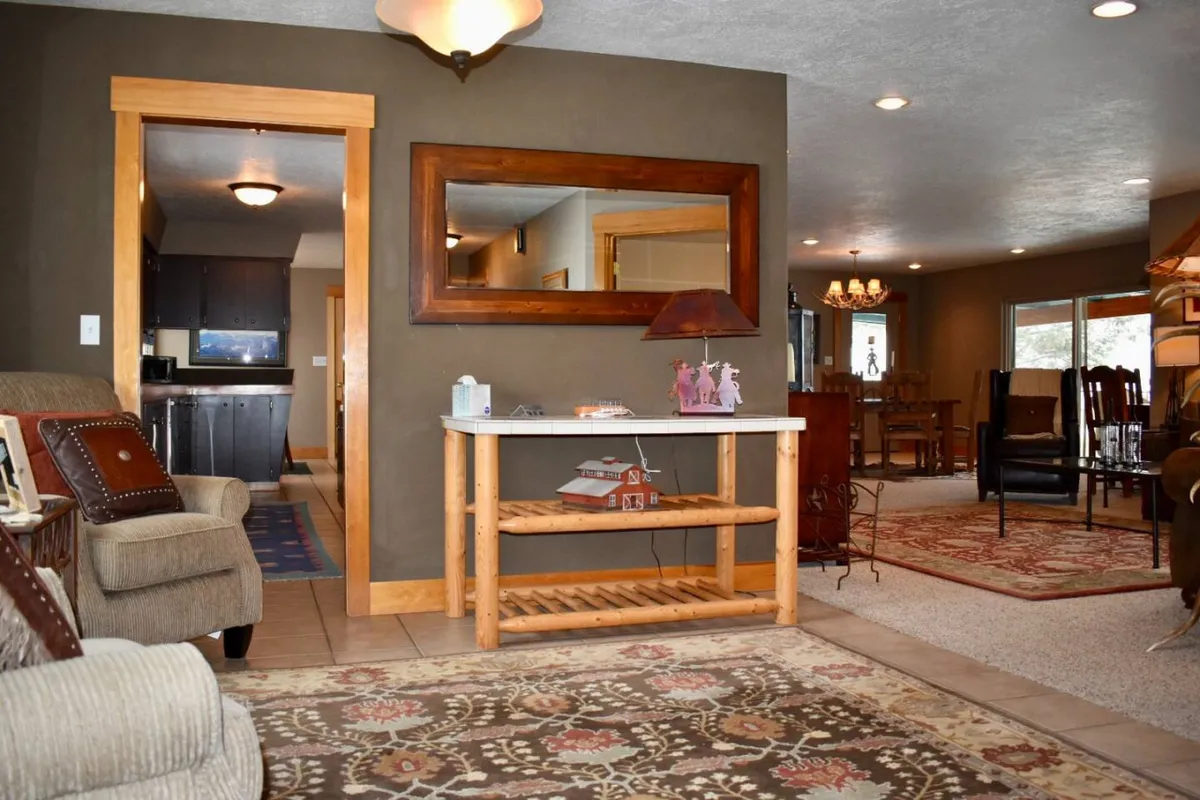 A cozy dining nook with a wooden table, decorative lamp, and patterned seating. The mirror and soft lighting create an inviting space for casual meals, board games, or relaxed conversations.