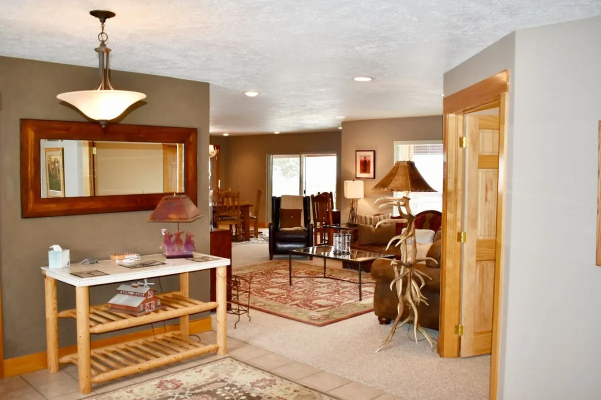 A thoughtfully arranged seating area centered around a bamboo-style table, with a decorative lamp and a prominent wooden mirror. The warm tones and rustic elements set a tranquil, inviting atmosphere ideal for gatherings or quiet reflection.